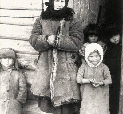 Eine Frau mit mehreren Kindern vor ihrem Haus.
